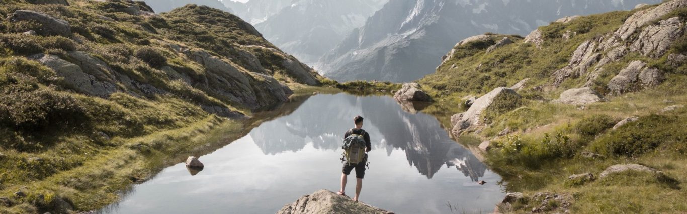 Ein Wanderer steht an einem Bergsee.